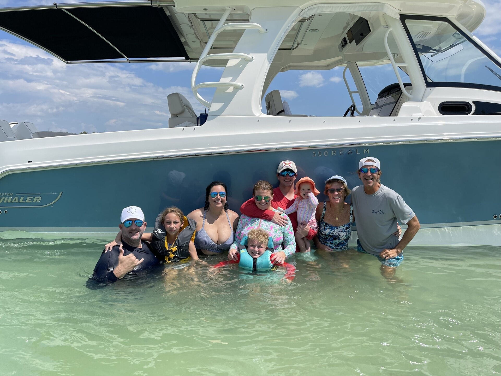 A family standing in the water in front of their 350 Realm from Boston Whaler
